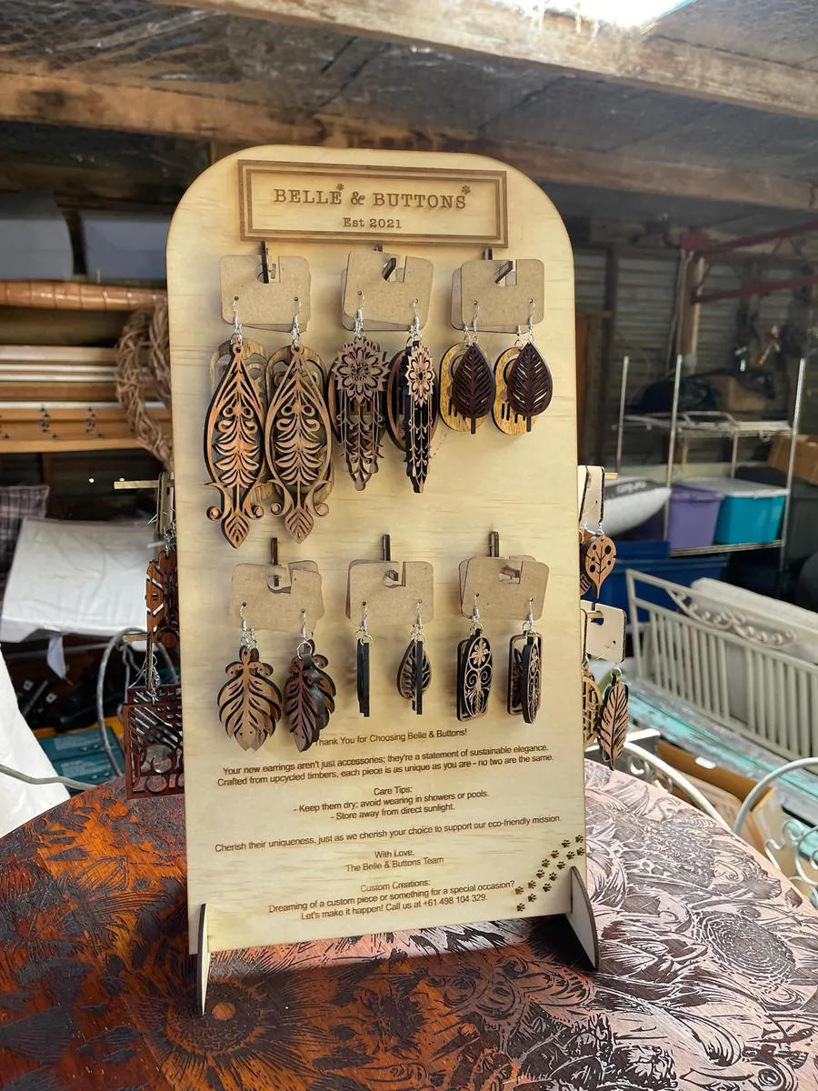 Branded laser cut timber earring retail display stand engraved with logo and care instructions, holding laser cut earrings