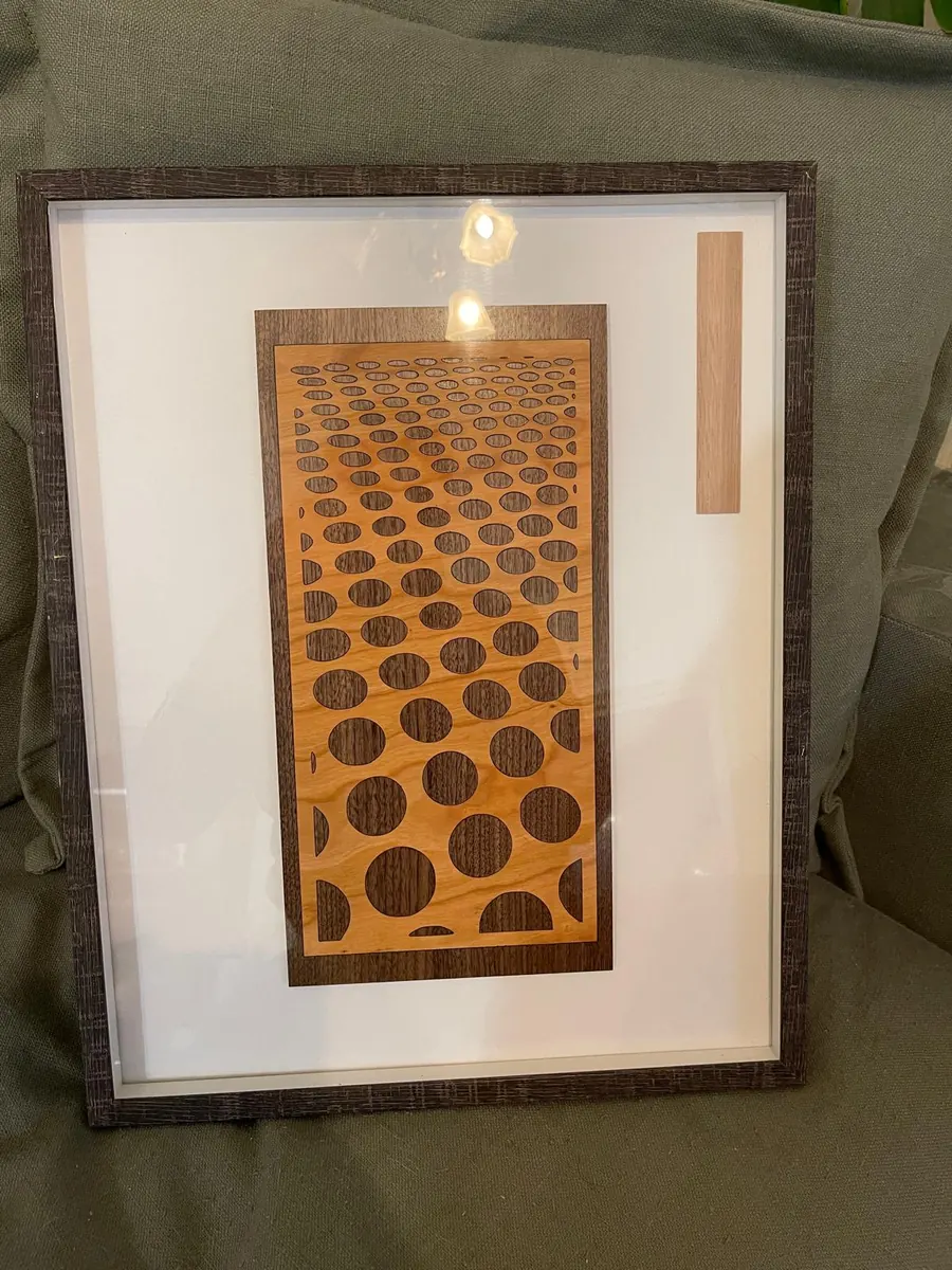 Laser cut honeycomb pattern wall art with graduated circles inlaid in cherry and walnut timber, framed