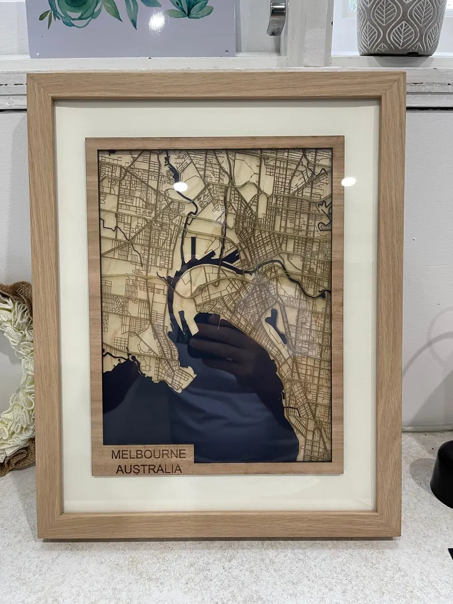 Framed laser cut map of Melbourne, Australia in layered timber with dark blue water and an engraved name plate