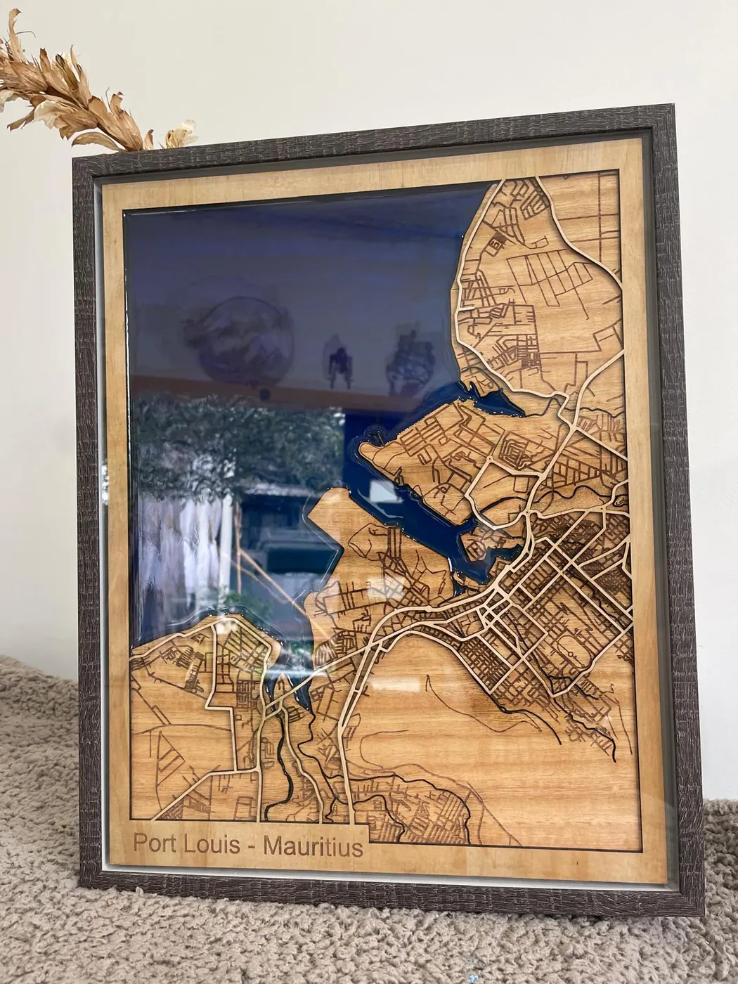 Framed layered laser cut map of Port Louis, Mauritius in timber with a deep blue resin harbour and the place name engraved along the base