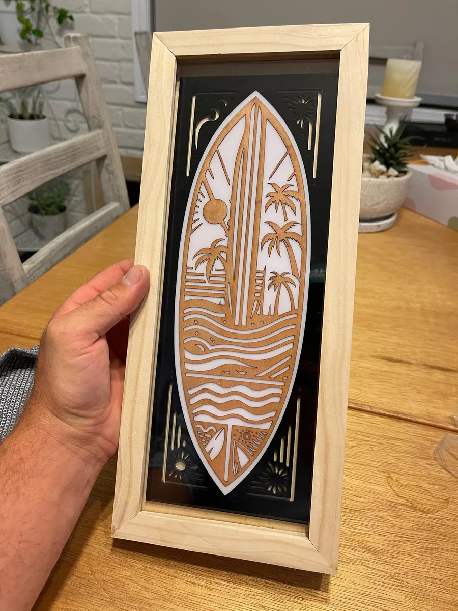 Framed laser cut surfboard wall art in timber over a white panel with palm trees and wave linework