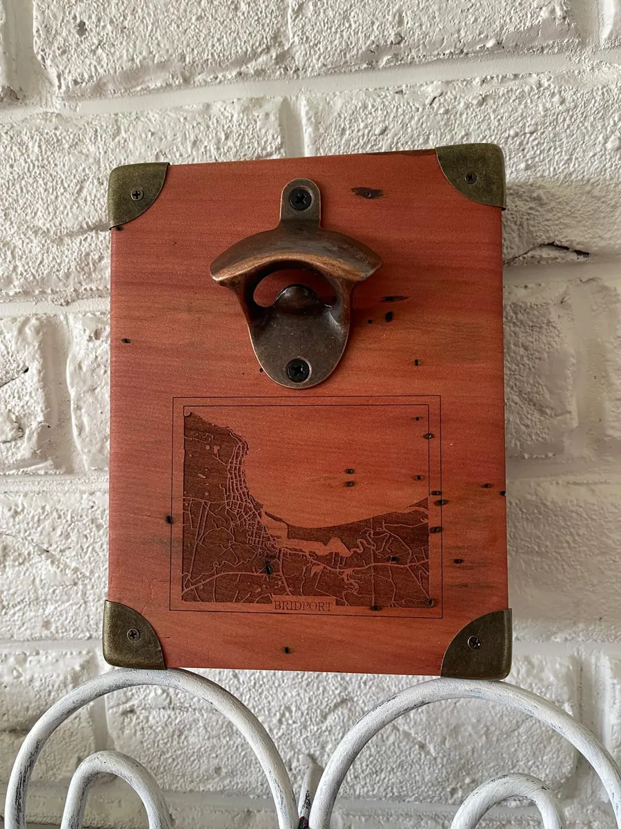 Wall mounted bottle opener on a stained timber board with a laser engraved map of Bridport, Tasmania beneath it