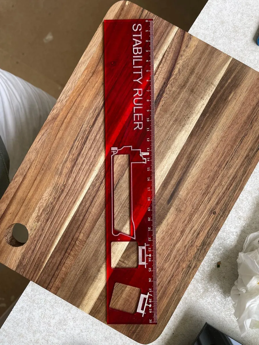 Red cast acrylic ship stability ruler with a laser engraved measurement scale and cut-out vessel profile